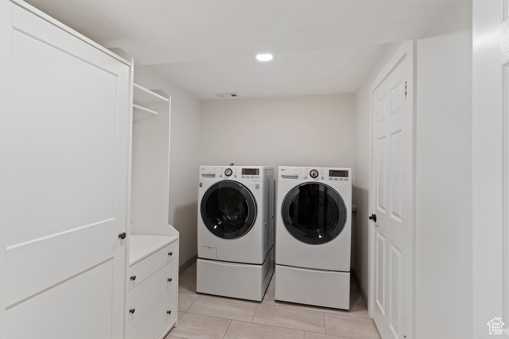 Laundry area featuring washing machine and dryer, light tile patterned flooring, and recessed lighting