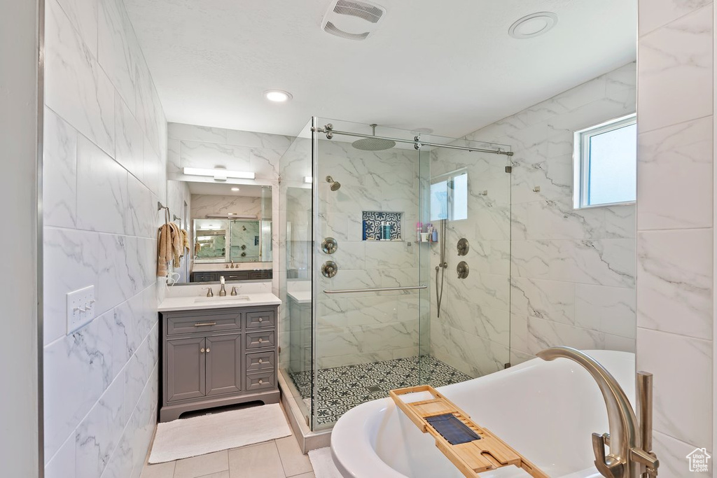 Full bath featuring a marble finish shower, vanity, a tub, recessed lighting, and tile walls