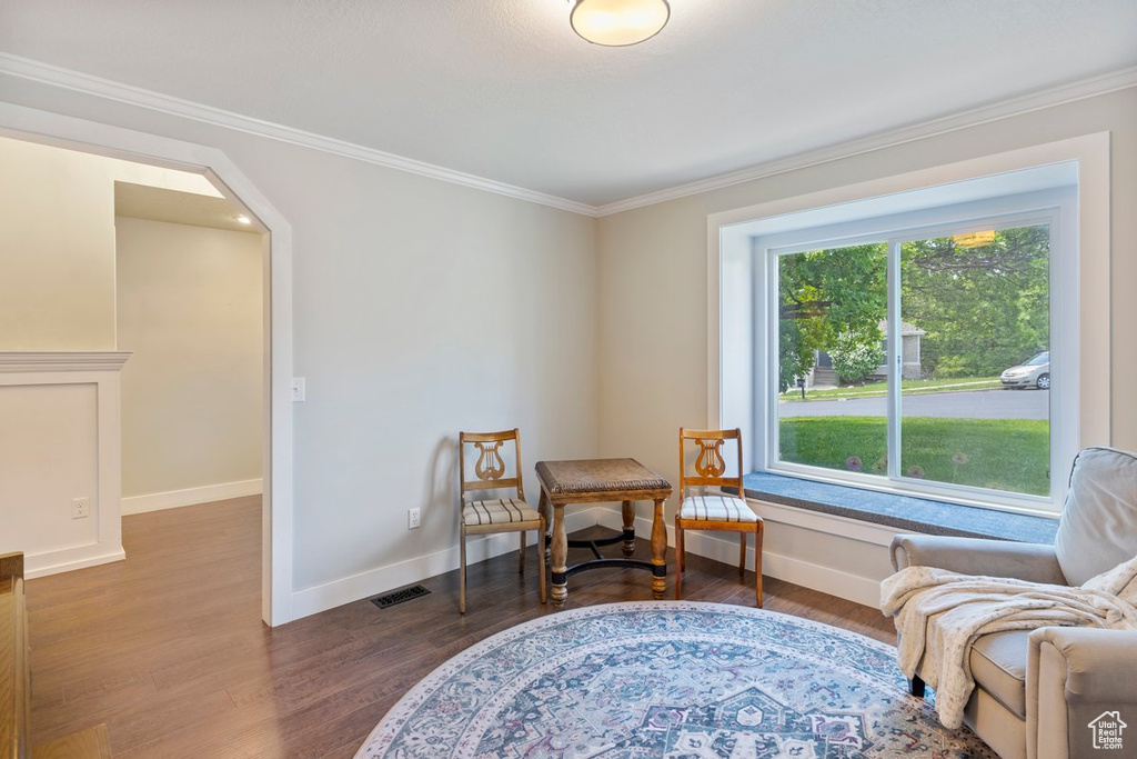 Sitting room featuring dark wood-type flooring, ornamental molding, arched walkways, and baseboards