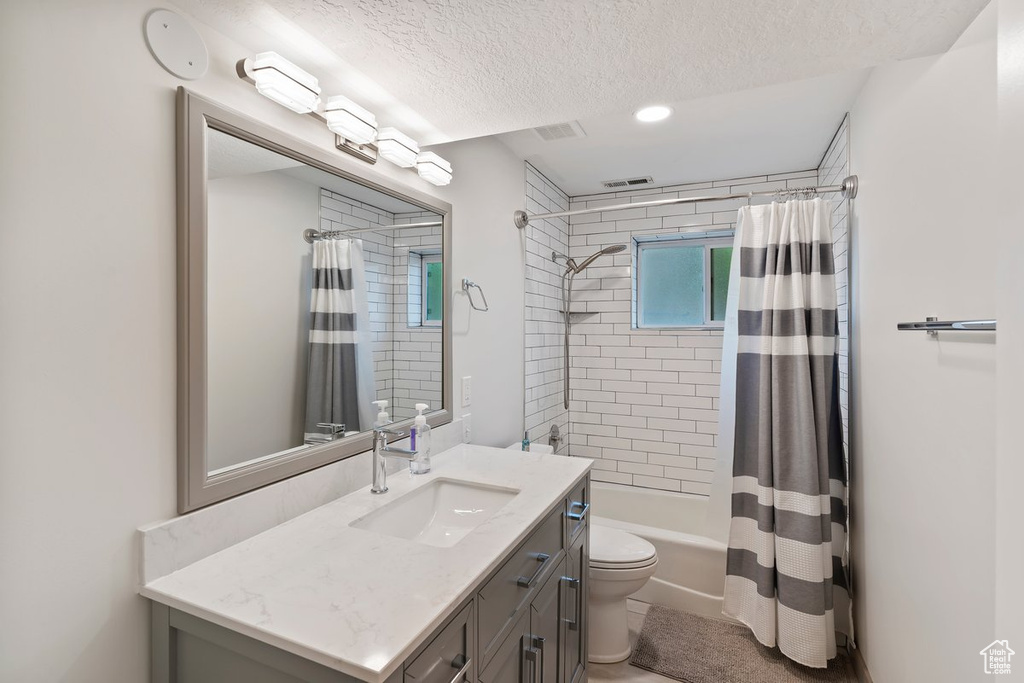 Bathroom with toilet, vanity, a textured ceiling, shower / tub combo, and recessed lighting