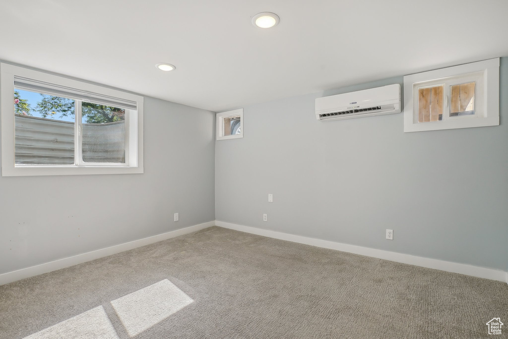 Carpeted empty room featuring an AC wall unit, recessed lighting, and baseboards