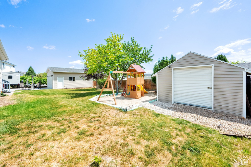 View of grassy yard with an outbuilding and a playground