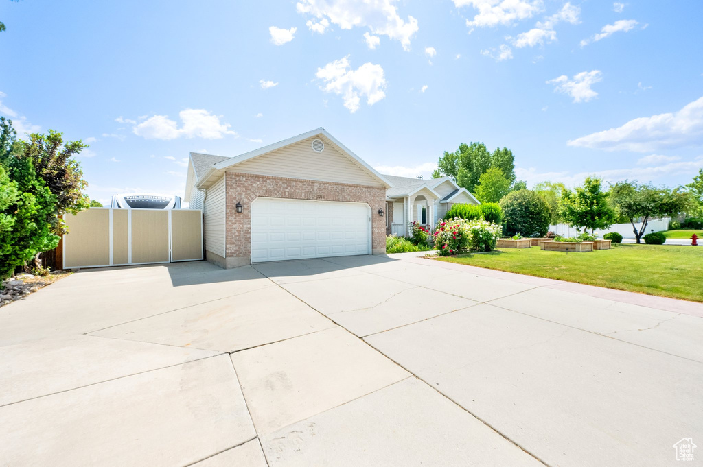 Single story home featuring concrete driveway, brick siding, an attached garage, and a gate