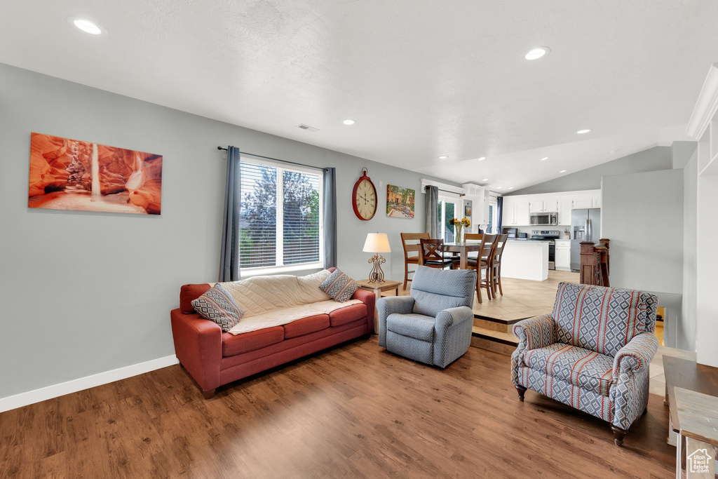 Living room with recessed lighting, light wood-type flooring, and vaulted ceiling