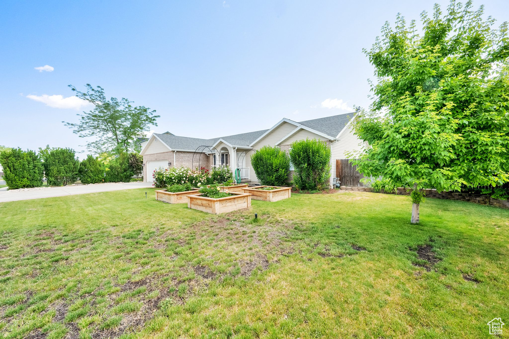 Single story home featuring an attached garage, a vegetable garden, and driveway