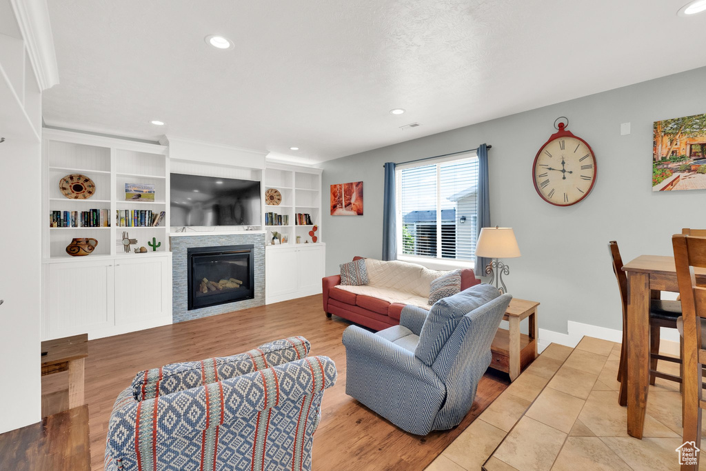 Living room featuring a glass covered fireplace, recessed lighting, wood finished floors, and baseboards