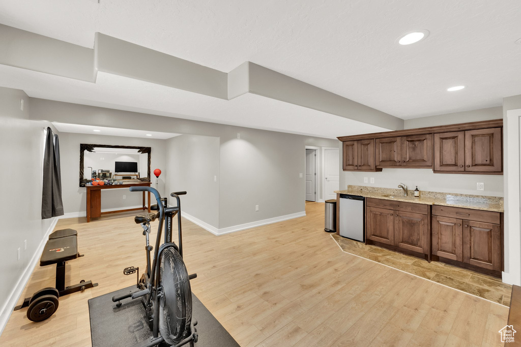 Exercise room featuring light wood finished floors, baseboards, a sink, and recessed lighting