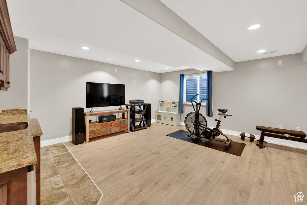 Exercise area featuring baseboards, recessed lighting, a sink, and light wood-type flooring