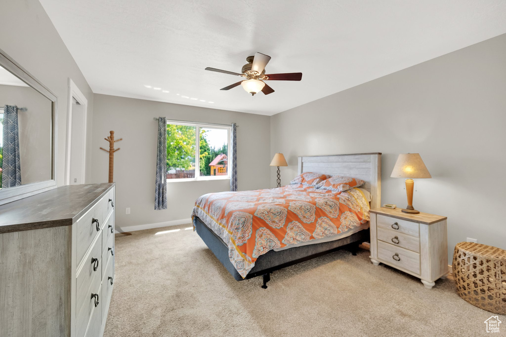 Bedroom featuring light carpet, baseboards, and ceiling fan