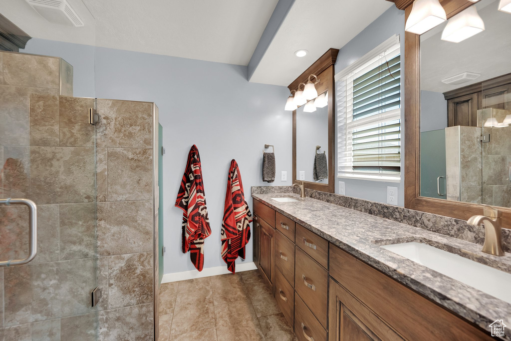 Full bathroom with double vanity, a shower stall, and baseboards