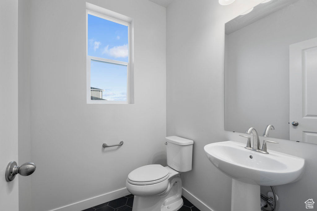 Bathroom with baseboards, toilet, plenty of natural light, and tile patterned flooring