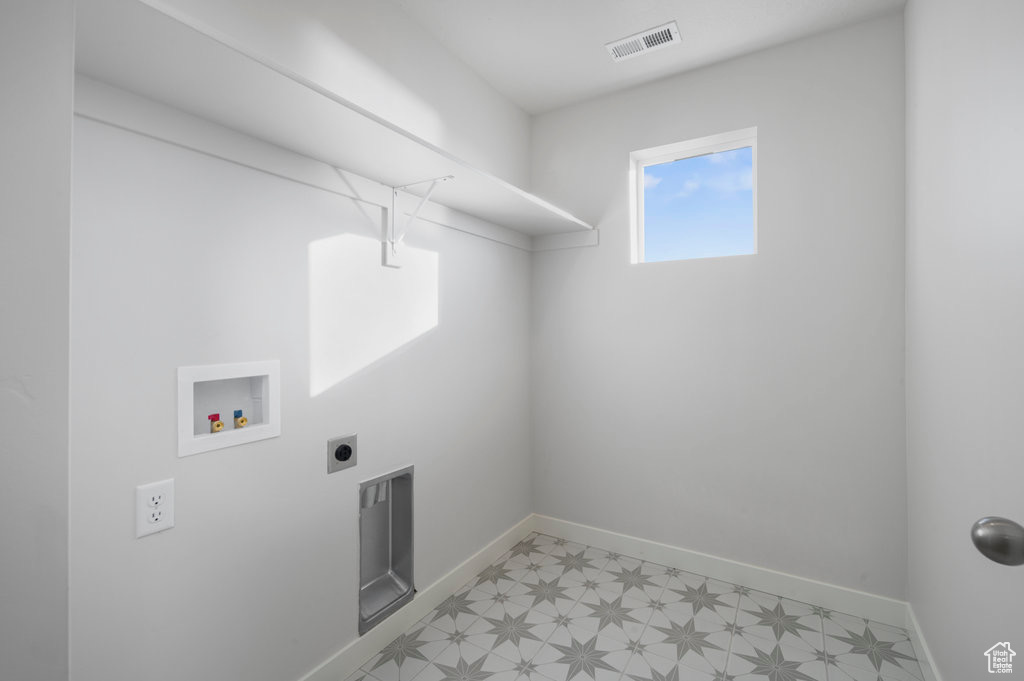 Washroom with hookup for a washing machine, light flooring, baseboards, and hookup for an electric dryer