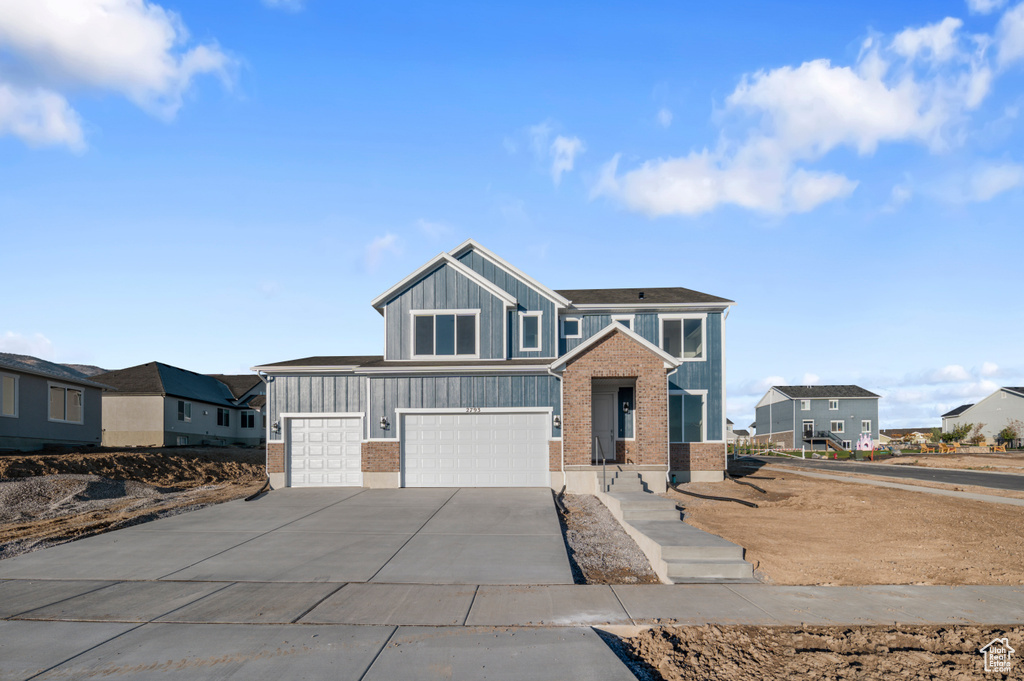 View of front of house with concrete driveway, brick siding, a residential view, and a garage