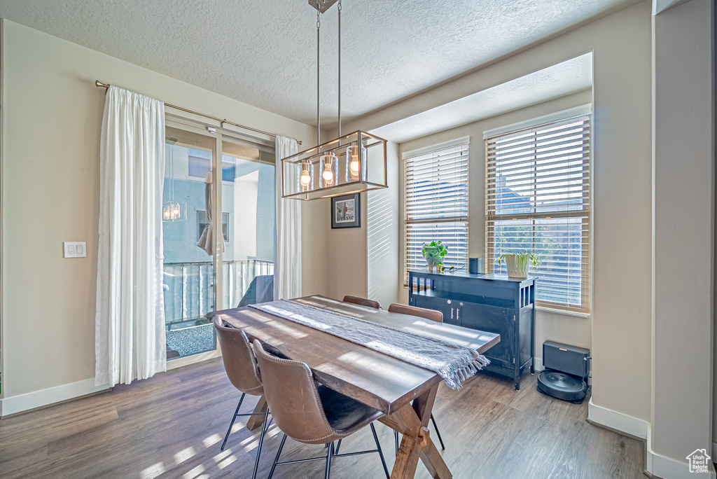 Dining area featuring baseboards, wood finished floors, and a textured ceiling