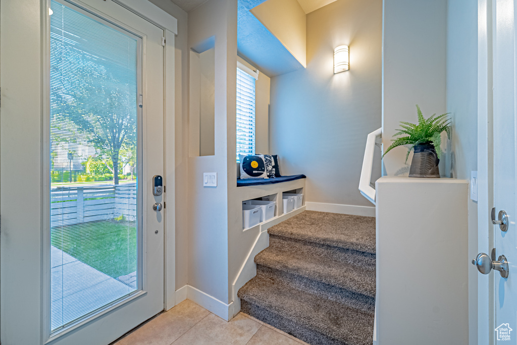 Doorway to outside with stairway, light tile patterned floors, and baseboards