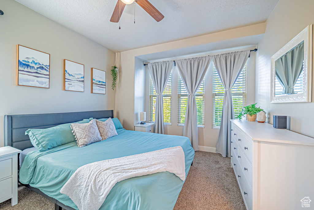 Bedroom with light carpet, a ceiling fan, and baseboards