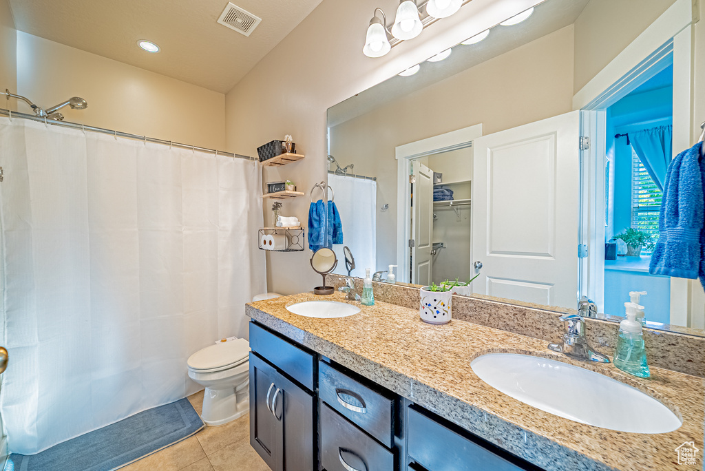 Full bath with double vanity, toilet, and tile patterned flooring