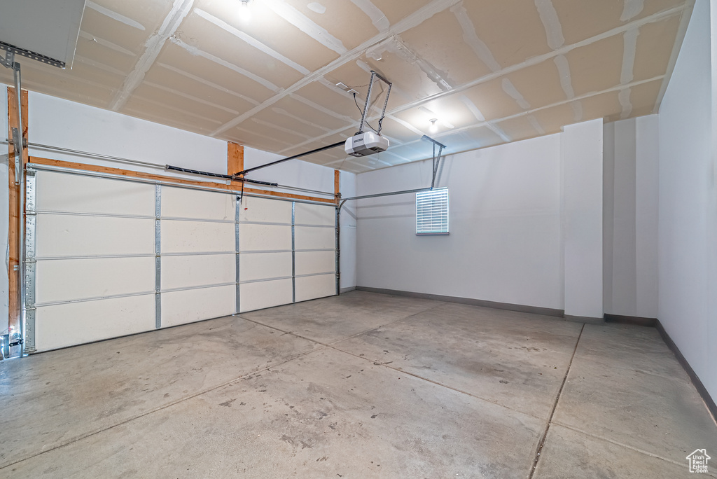 Garage featuring a garage door opener and baseboards