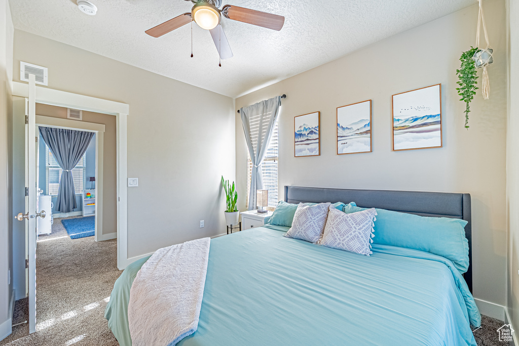 Carpeted bedroom featuring baseboards, a ceiling fan, and a textured ceiling
