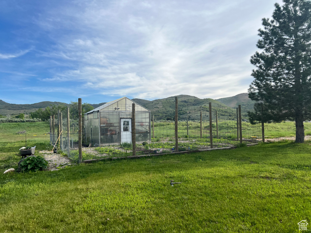 View of greenhouse with a mountain view, a yard, and a garden