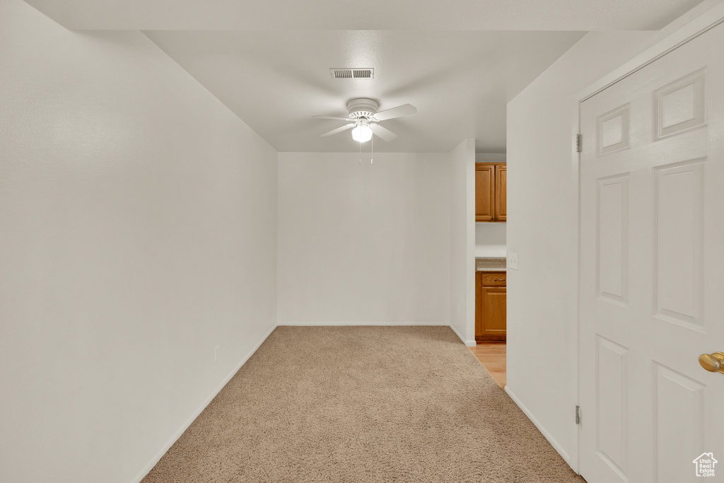 Unfurnished room with light colored carpet, ceiling fan, and baseboards