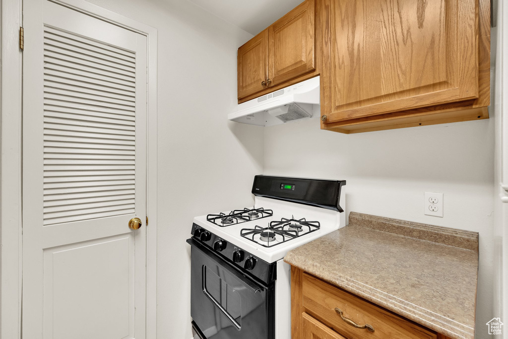 Kitchen featuring range with gas cooktop, under cabinet range hood, and light countertops