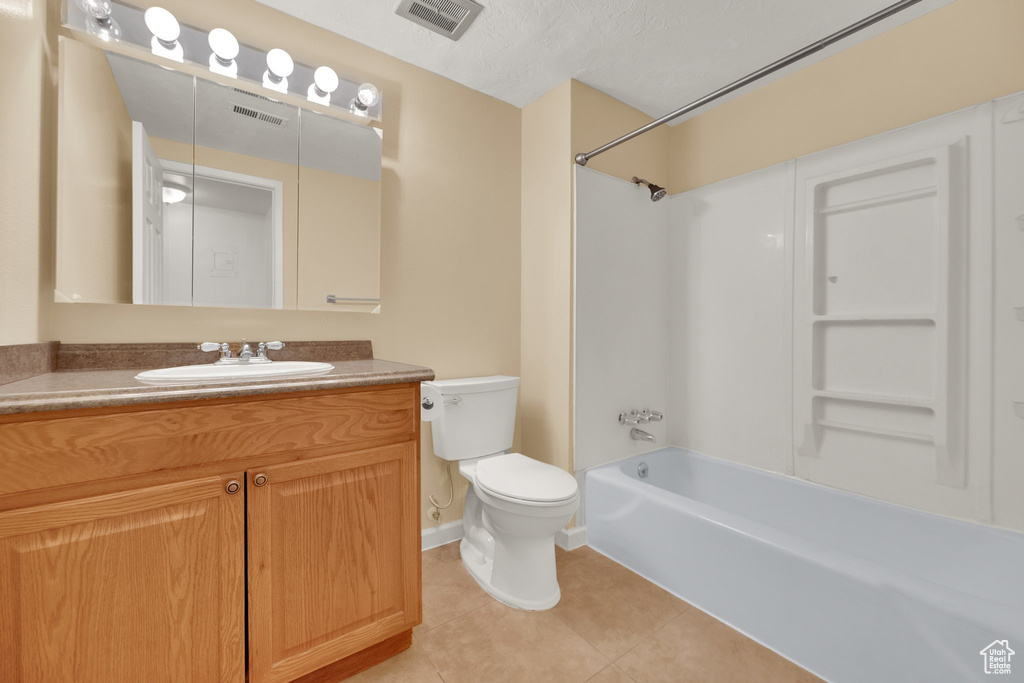 Bathroom with tile patterned flooring, vanity, toilet, and washtub / shower combination