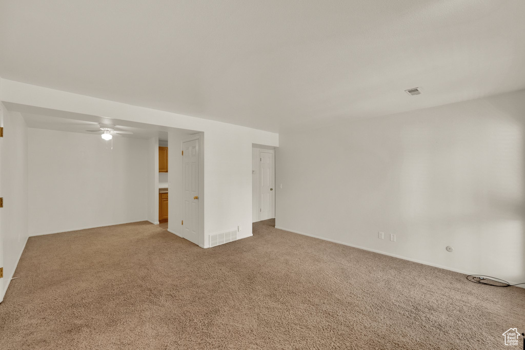 Unfurnished room with light colored carpet, ceiling fan, and baseboards