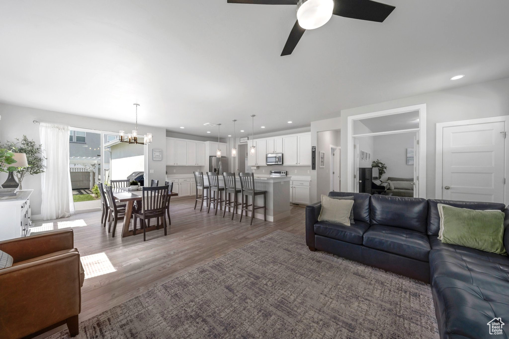 Living room featuring a chandelier, light wood finished floors, a ceiling fan, recessed lighting, and a desk