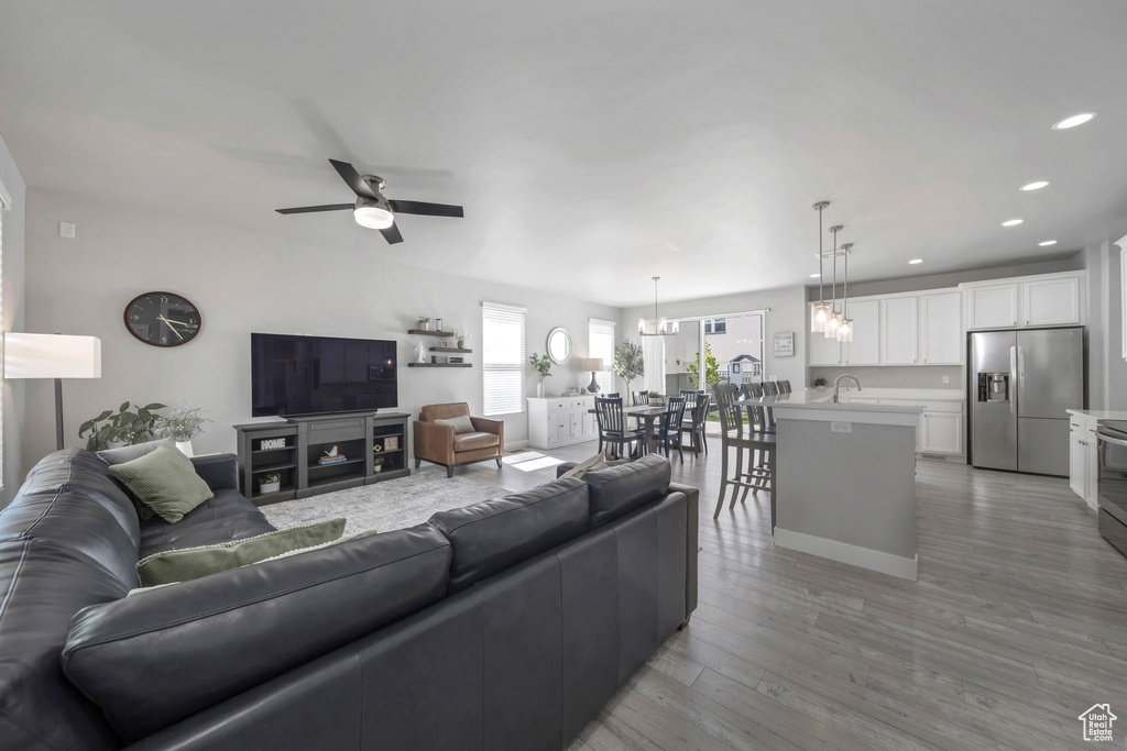 Living room with ceiling fan, light wood-type flooring, recessed lighting, and a chandelier