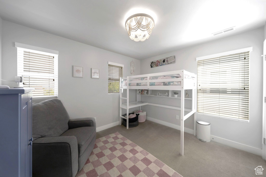 Bedroom with light carpet, baseboards, multiple windows, and a chandelier