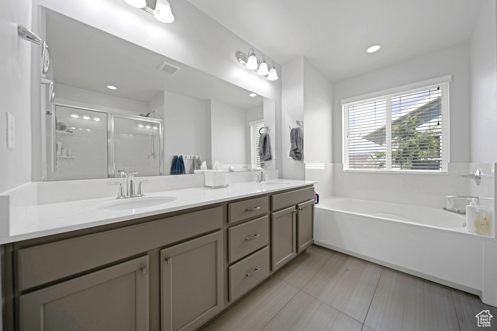 Bathroom with a bath, double vanity, a stall shower, and recessed lighting