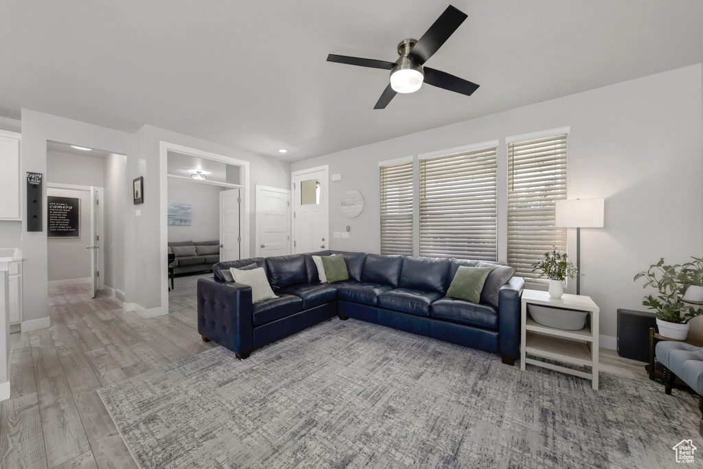 Living room with ceiling fan, light wood-style floors, and baseboards