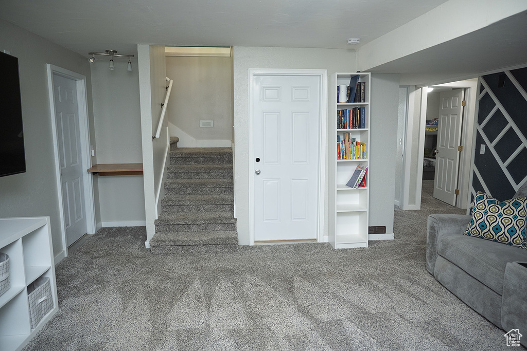 Carpeted living room featuring stairway and baseboards