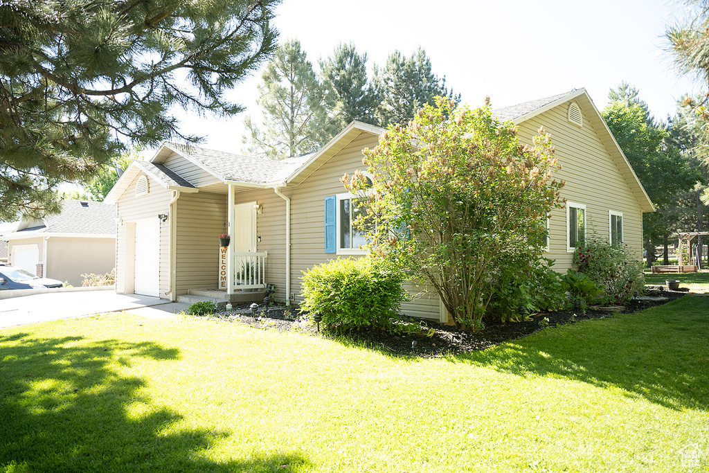 Ranch-style house with an attached garage, a front lawn, driveway, and roof with shingles