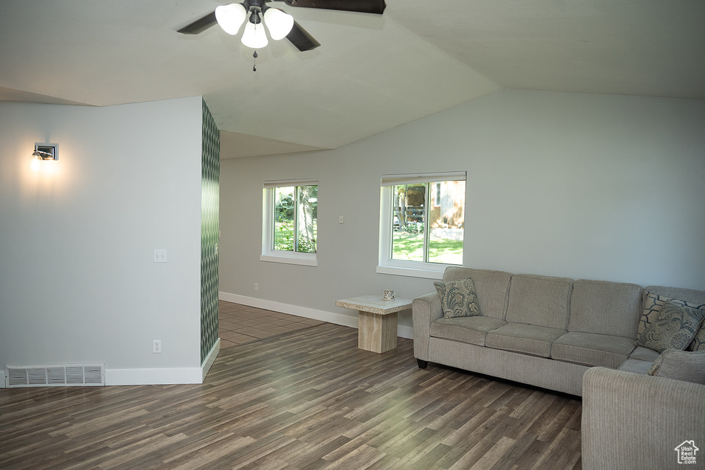 Living area featuring a ceiling fan, dark wood-type flooring, and lofted ceiling