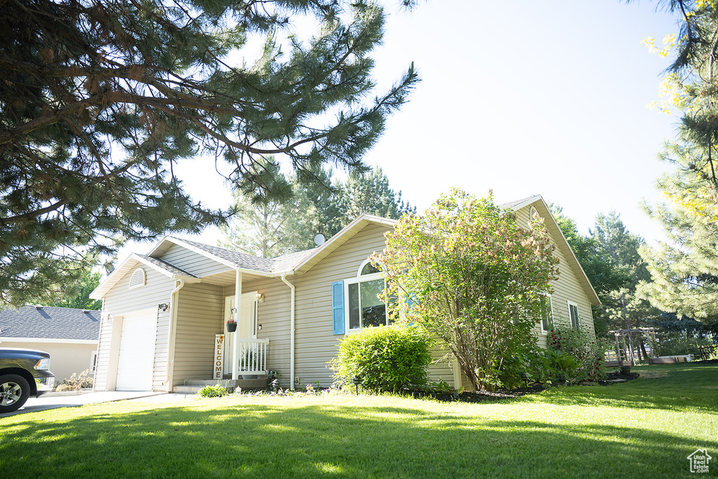 Ranch-style house featuring a garage, a front lawn, and driveway