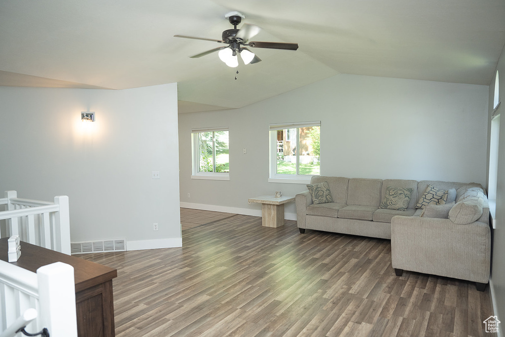 Living area with a ceiling fan, wood finished floors, and lofted ceiling