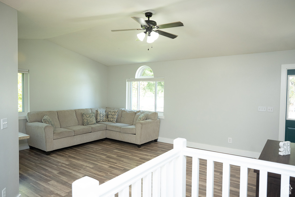 Living area with a ceiling fan, dark wood finished floors, and lofted ceiling