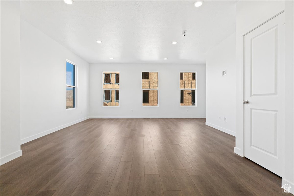 Unfurnished living room featuring plenty of natural light, recessed lighting, dark wood-style floors, and baseboards