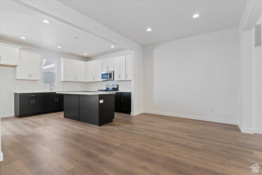 Kitchen featuring appliances with stainless steel finishes, white cabinets, light wood-style floors, a sink, and light countertops