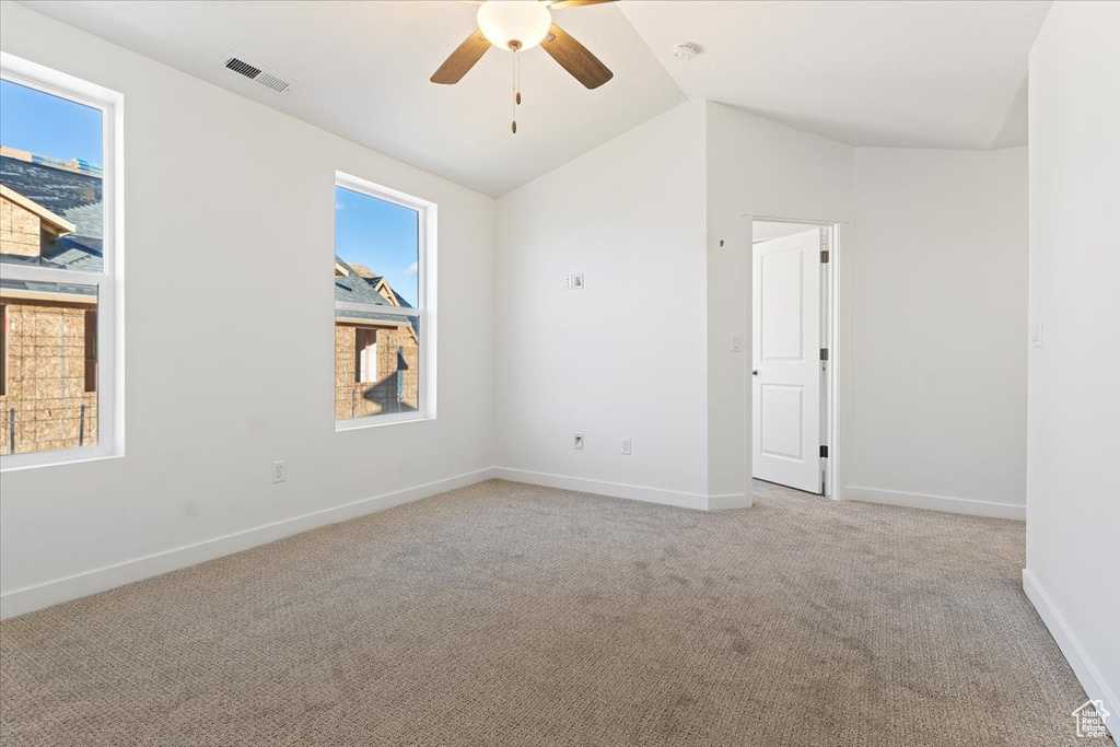 Unfurnished room with light colored carpet, lofted ceiling, a ceiling fan, baseboards, and a smoke detector