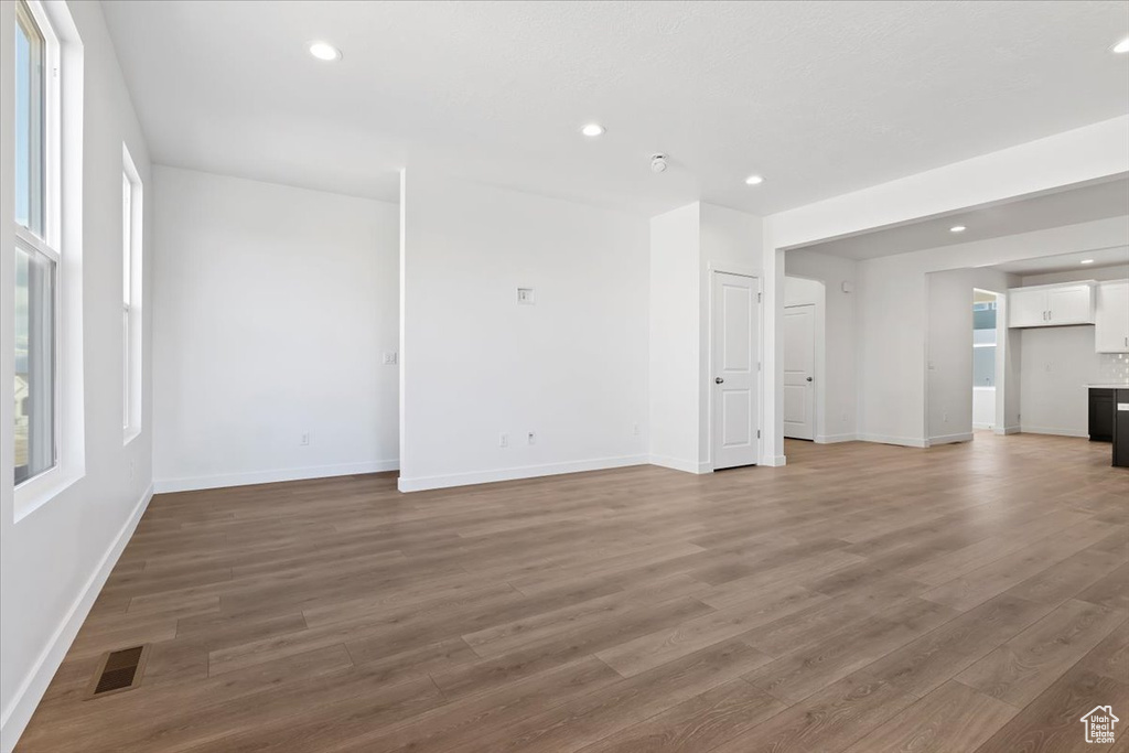 Unfurnished living room featuring light wood-style flooring, baseboards, recessed lighting, and healthy amount of natural light