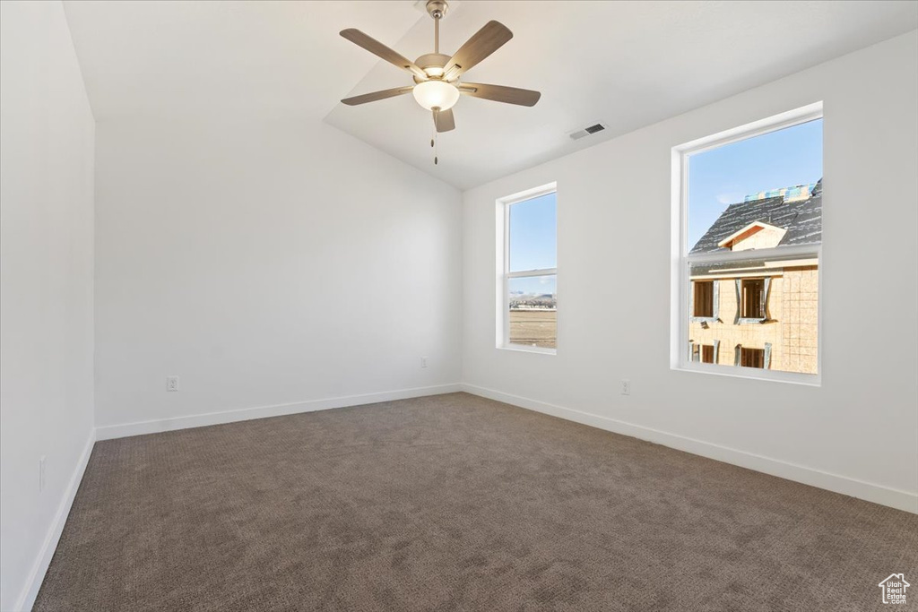 Spare room with carpet flooring, vaulted ceiling, baseboards, and a ceiling fan