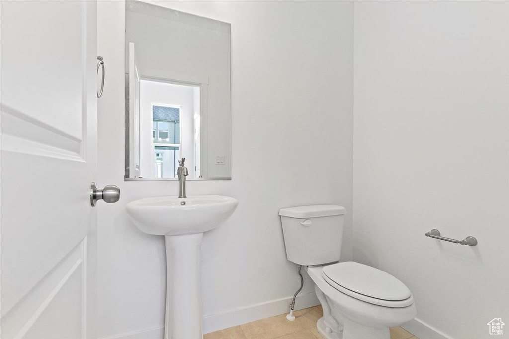 Bathroom featuring toilet, baseboards, and tile patterned flooring