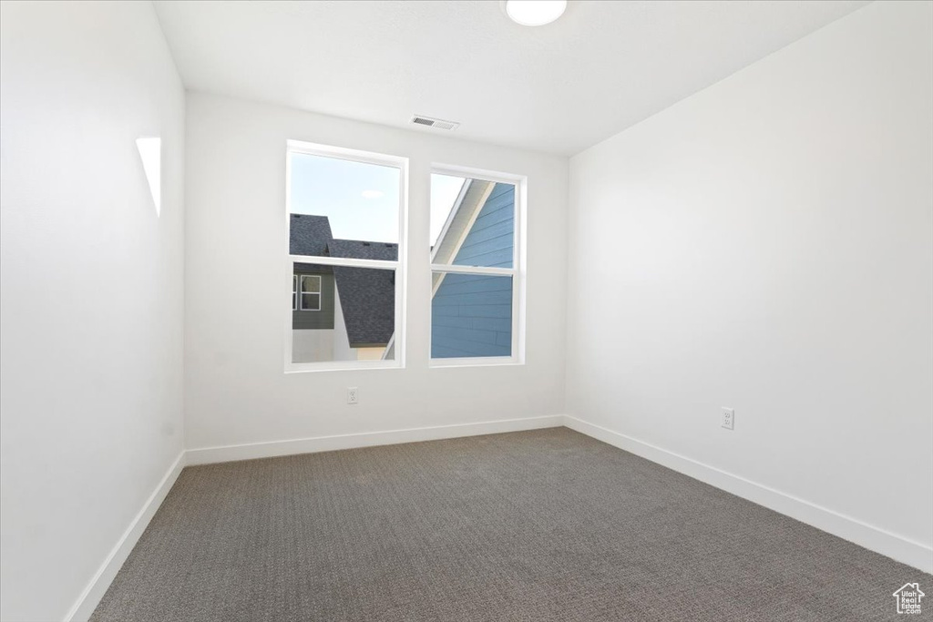 Spare room featuring baseboards and dark carpet