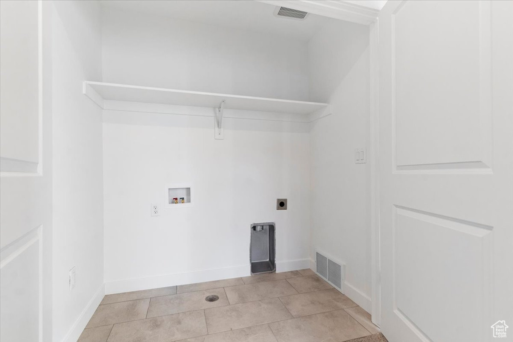 Laundry area featuring hookup for a washing machine, hookup for an electric dryer, light tile patterned floors, and baseboards