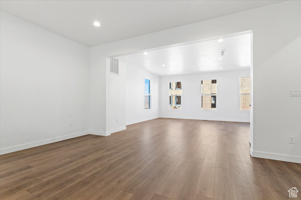 Unfurnished living room with dark wood-style floors, baseboards, and recessed lighting
