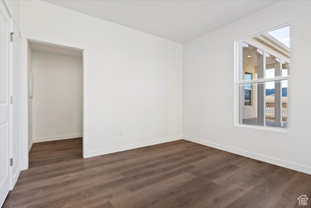 Unfurnished room with dark wood-type flooring and baseboards
