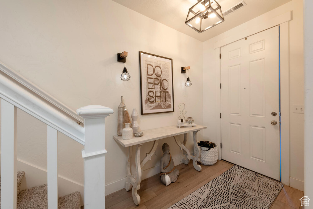 Entryway featuring light wood-style flooring, stairs, baseboards, and a chandelier